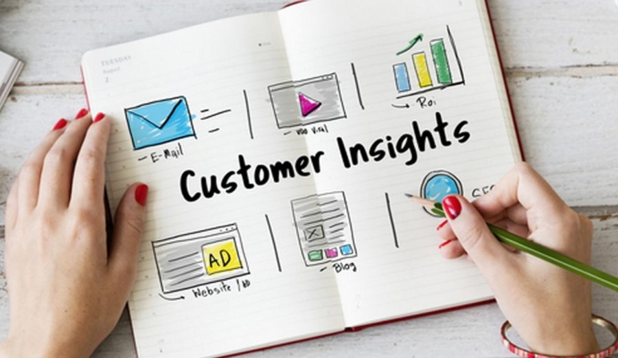  A woman's hand holding a pencil next to a notebook with a hand-drawn chart about customer insights from digital marketing research.